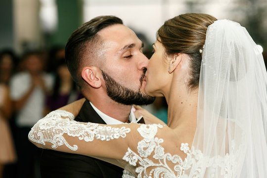 Passionate kiss of gorgeous wedding couple after their first dan