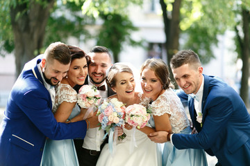 Tighty hugs of newlyweds, groomsmen and bridesmaids standing in