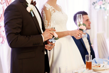 Bride and groom hold champagne flutes in their hands standing at