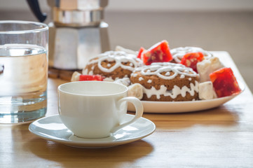 Holiday breakfast serving. Espresso cup, cookies and sweets, glass of water and italian moka coffee pot on natural wood table served for a christmas breakfast