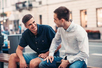 Friends talking together on a bench in the city