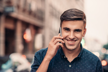 Smiling young man talking on his cellphone in the city