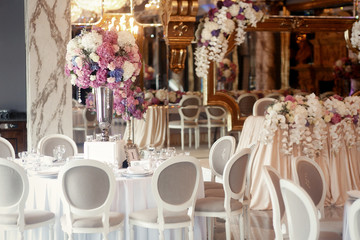 Grey chairs stand around round tables prepared for wedding dinne
