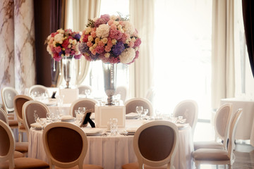 Round dinner tables with bouquets of pink and white flowers stan