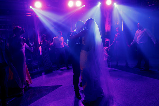 Blue light shine over wedding couple dancing in the darkness