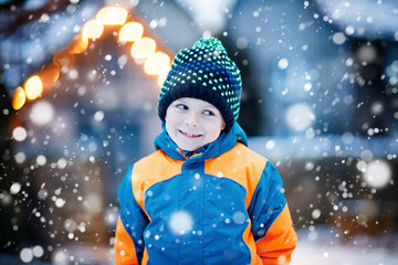Happy kid boy having fun with snow in winter