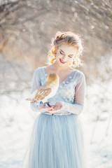 Fototapeta na wymiar Bride in a blue wedding dress, keep the owl on her hands.