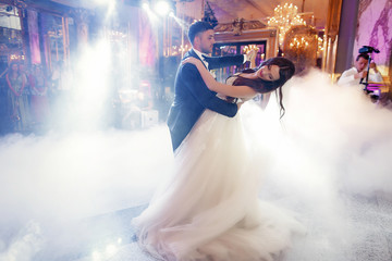 Groom bends gorgeous bride over dancing in the smoke