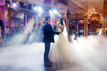 Bride reaches her hands to groom dancing in luxurious hall