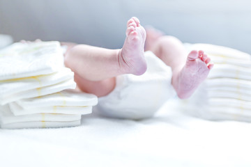Feet of newborn baby on changing table with diapers - obrazy, fototapety, plakaty