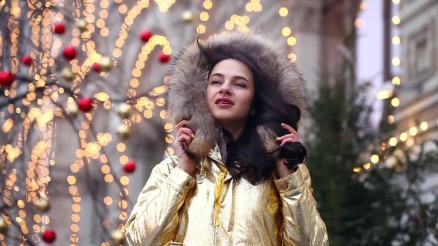 Portrait close up of young beautiful brunette woman in golden fur coat, winter outdoors