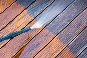 cleaning terrace with a power washer - high water pressure cleaner on wooden terrace surface