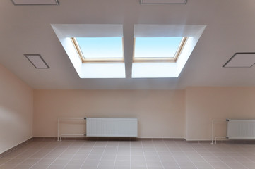 Modern interior of attic room with a sloping ceiling and skylight. 