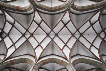 Arched ceiling of gothic church. Stone frame and white filling. Symmetrical form, look up.