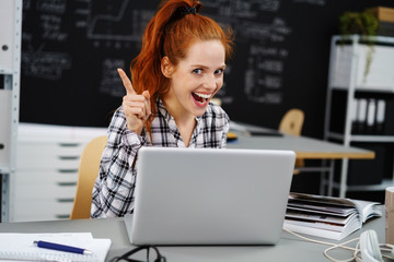 lachende frau sitzt am schreibtisch und hat eine idee