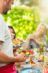 Focus on a man serving dishes of food to a group of friends © jackfrog
