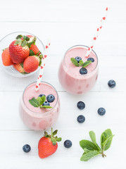 Stylish glasses of healthy smoothies with strawberry and blueberry. Morning breakfast for two. Top view