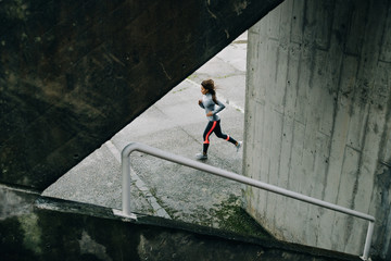 Sporty woman running on winter rainy day. Urban female athlete exercising on asphalt. - 133096977