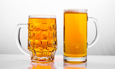 Two Mugs of fresh beer with cap foam