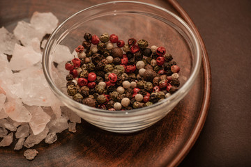 Set of whole peppercorns and rose salt. Handful of red, black, white peppercorns and salt on a argil plate. Herbs and spices concept