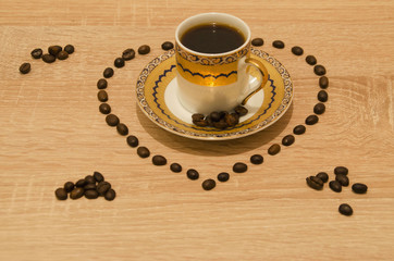 Cup of your favorite coffee with a saucer and a heart on coffee beans