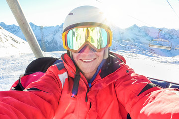 Happy skier taking selfie photo with smart cell phone camera