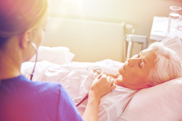 Obraz na płótnie Canvas nurse with stethoscope and senior woman at clinic