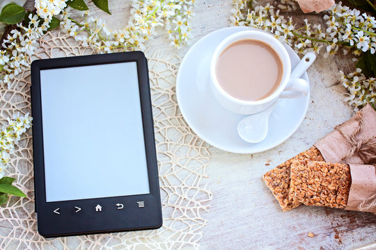 Cup of coffee and the e-book reader on a table