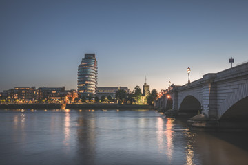 Putney bridge connecting Fulham and Putney. Glossy River thames during the sunset