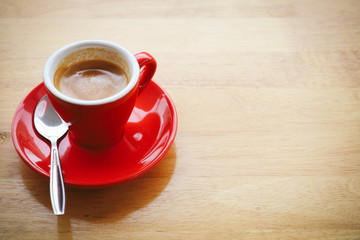 Red cup Espresso on wooden table for copyspace. Vintage tone. Selective Focus.
