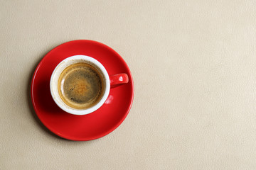 Red cup of Espresso on light brown seat leather.