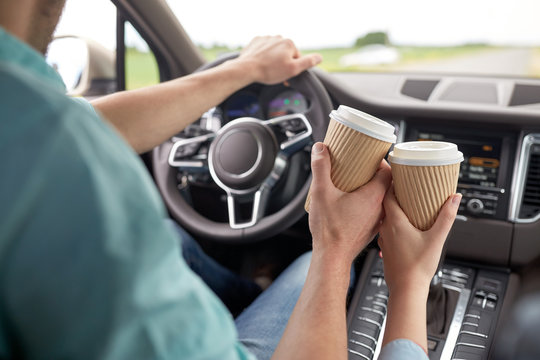 Close Up Of Couple Driving In Car With Coffee Cups