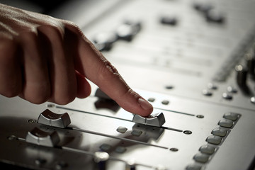 hand with mixing console in music recording studio