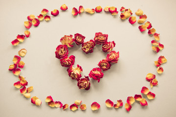 Valentine's card. Heart symbol made of dried roses on a vintage background. Top view, flat lay. Concept, postcard with place for your text. Vintage filter.