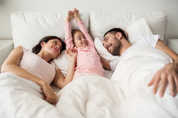 happy family waking up in bed at home - Powered by Adobe