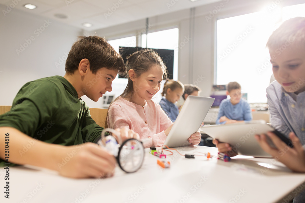 Poster kids with tablet pc programming at robotics school