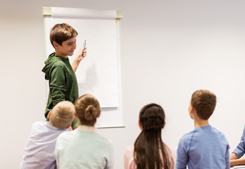student boy with marker writing on flip board
