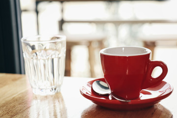 Red cup of espresso on wooden table in coffee cafe. selective focus. Vintage tone.