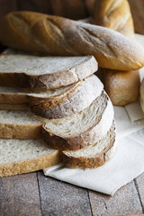 Fresh baked bread and sliced bread on rustic wooden table