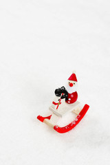 Toy Santa Claus with rocking horse on a snow pile