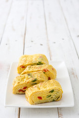 Traditional tamagoyaki Japanese omelette on white wooden table.
