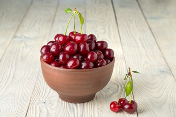 ripe cherries in a bowl on a wooden background