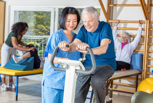 Asian nurse helping elder man in hospital gym