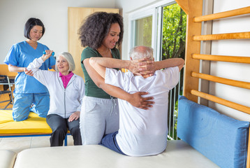African nurse helping elder man with with physical exercises in