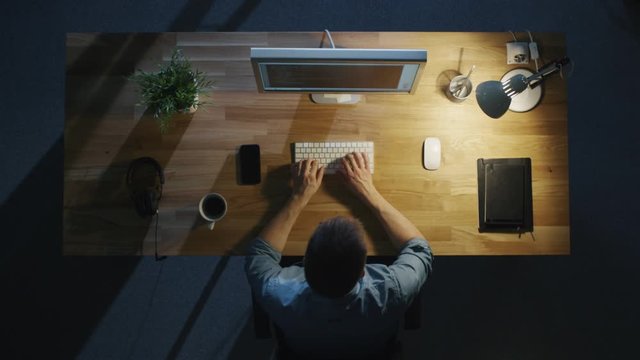 Top View of a Programmer Writing Code on His Personal Computer at Night. Table Light Turned On.  Shot on RED Cinema Camera in 4K (UHD).