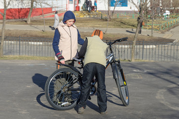 older brother helps younger brother to learn to ride a bike