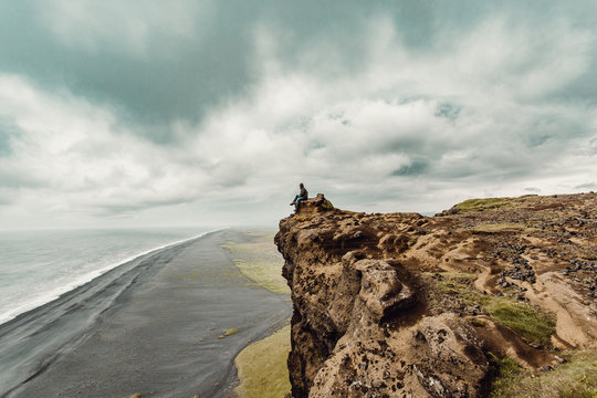 Man sitting on cliff and looking at sea