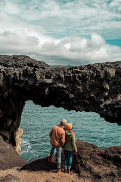 Couple looking through natural arch at sea 