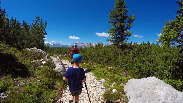 Hiking people - hiker couple father and son in beautiful landscape. Hikers man and child trekking walking with backpacks in trail in mountains. Dolomites, Alps, Italy