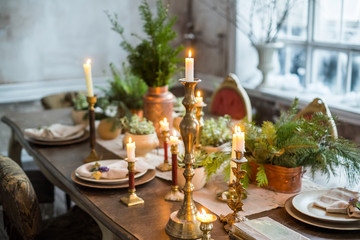 Festive table setting by candlelight, indoor. Winter decoration in rustic style